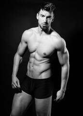 Fototapeta premium Handsome young muscular bodybuilding man posing in underwear with visible six pack in black and white