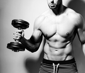 Shirtless  fit bodybuilder horse lifting dumbbell showing muscles and six-pack after workout