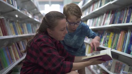 Little boy in glasses and his mother are choosing book