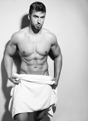 Handsome young man posing shirtless with towel after workout showing off fit muscles