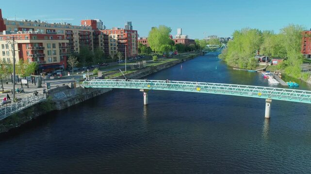 People walk across a pedestrian bridge over the Lachine Canal in Montreal, Canada. The canal is a popular spot for recreation and tourism. Atwater Market.