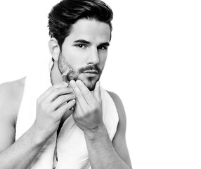 Handsome young man shaving his beard after shower 