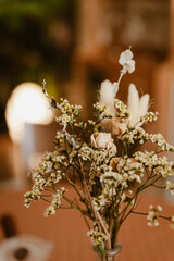 spring dried flowers in a vase, floral decoration art in a warm tone background, wooden table and bright yellow light in the back