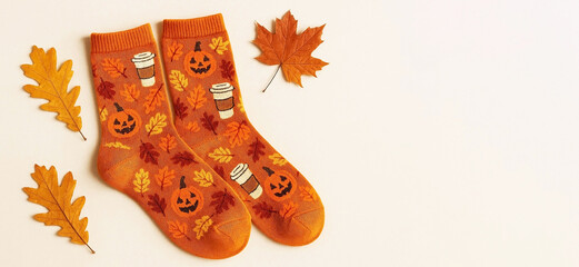 Colorful cotton socks with a decorative Halloween pattern in the form of orange pumpkins, black cats, bats, autumn leaves and ghosts, on a light background, fun Halloween clothes