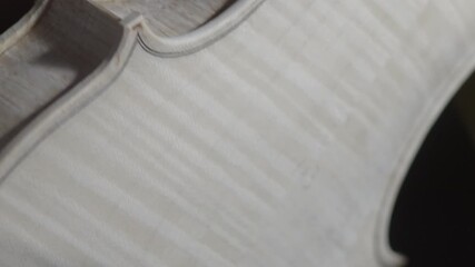 Experienced craftsman carefully sanding violin body, showcasing intricate woodworking skills and traditional lutherie techniques with specialized handcrafting tool - Powered by Adobe