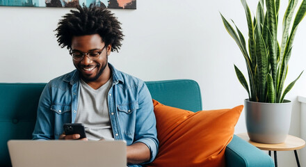 Man sitting on sofa at home using laptop and phone, enjoying a relaxed and connected lifestyle in a domestic setting