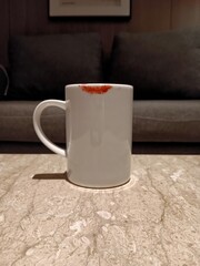 A cup of warm sweet tea on a marble table warms the morning as beautiful lip gloss clings to the cup.