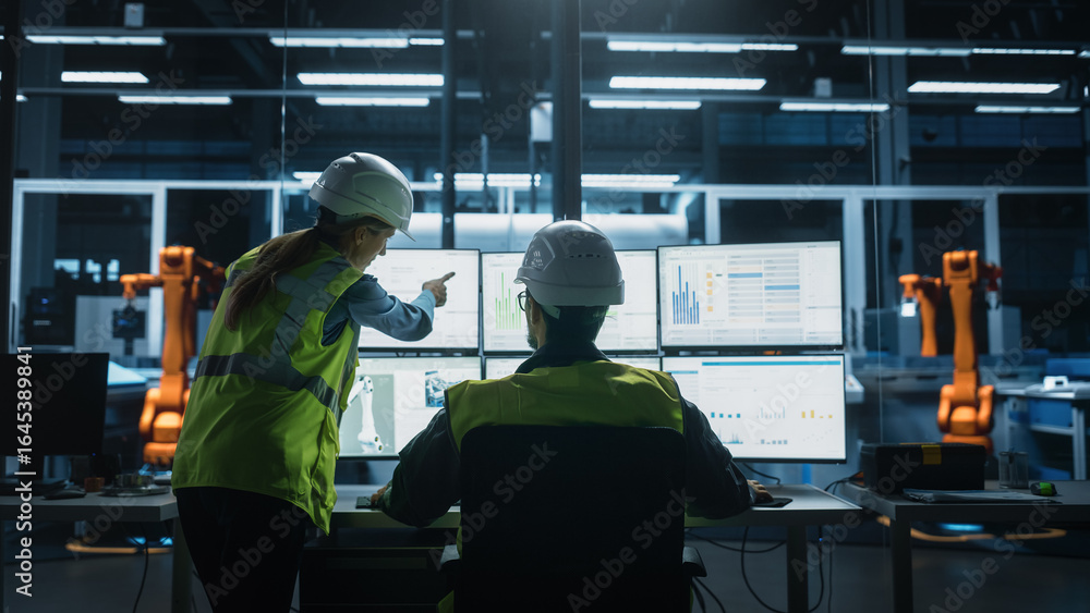 Poster caucasian male engineer using multi monitor workstation and talking to female production supervisor 