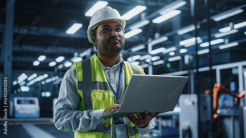 Poster portrait of thoughtful indian male engineer walking with a tablet computer, monitoring conditions at