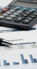 Close-up of financial report with pen and calculator, showcasing business data analysis, charts and numbers, representing financial planning and accounting concepts