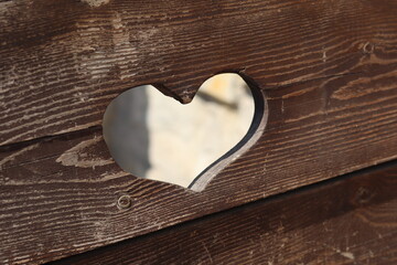 Heart-shaped opening in wooden fence allowing light to shine through at a garden