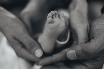 Minimal black and white close up of a newborn baby foot in parents hands. Perfect for maternity, healthcare, and baby product marketing, symbolizing love, safety, and new life. High quality photo