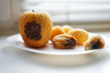 rotten fruits on a light background, apricot and apple