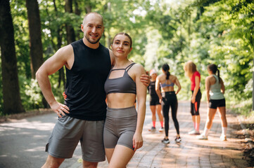 Obraz premium Couple is standing and embracing each other. Group of runners are together outdoors
