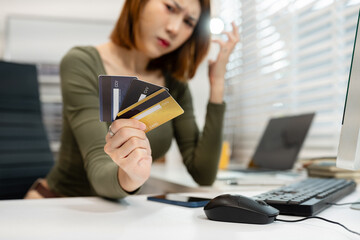 Asian woman stressed over credit card debt, holding bills in frustration. Financial anxiety and...
