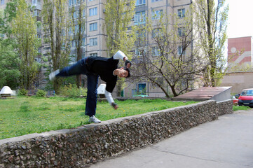 A guy does an acrobatic trick from a small ledge in the city	
