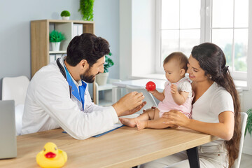 Young mother parent sitting with cute toddler child baby during medical examination in clinic....