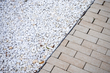 Architectural Background. Small white landscaping gravel stones and light beige paving stones clash...