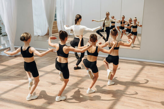 Looking at the mirror. Trainer is teaching girls ballet dancing