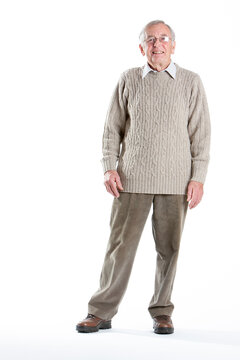 Elderly man in a knitted jumper. A senior man stands looking at the camera with a neutral expression.