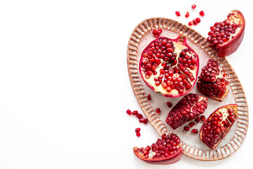Plate full of fresh ripe pomegranate with cut in half and pieces, top view.