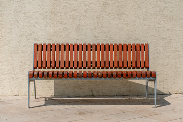 A bench against the background of a light wall of a building in summer, minimalism and the place of...