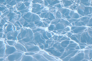 Clear blue water background, reflected ripple across the pool, top view of summer surface of swimming pool with sunlight, design for cosmetic product ,skincare wallpaper