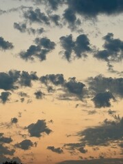 Dramatic sky at sunset with scattered dark clouds over a warm orange and blue background. A peaceful, moody atmosphere perfect for nature, weather, and scenic themes in creative projects.