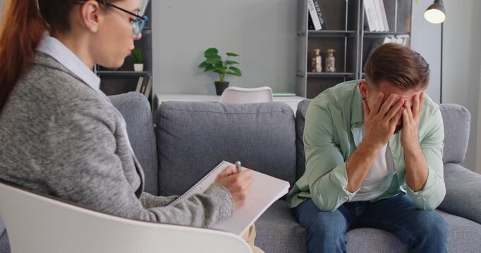 Young man attending a therapy session with a female psychologist. Concept of mental health support, emotional conversation, and psychological counseling in a cozy modern office. 