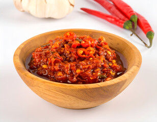 Traditional Indonesian chili paste sambal in wooden bowl with fresh chili peppers and garlic on white background. Generative AI