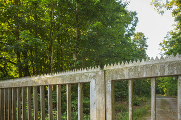 Old concrete fence with metal spikes protecting forest area