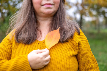 Happy mature woman with fall leaf in hand, Elegant senior lady, park background, vibrant aging,...