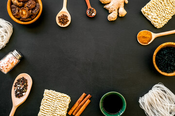 Chinese and Japanese food cooking with ginger, spices and noodles frame on black background top view space for text