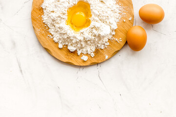 Making dough concept. Pile of flour and eggs on white background top view copy space