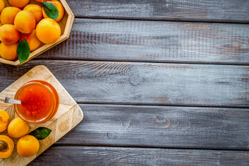 Healthy breakfast. Apricot jam in jar near fresh fruits on dark wooden background top view frame copy space