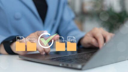 Businesswoman using a laptop to manage digital document folders with approval checkmark icons on a virtual screen, concept of data organization and verification © K2L Family