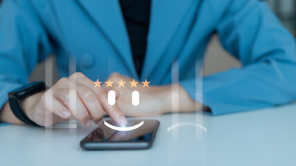 Customer using smartphone to give five-star rating with happy face icon on virtual screen, concept of positive feedback, service review, and satisfaction