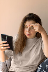 A teenage girl closely inspecting a blemish on her face in a bathroom mirror. Emphasizes acne care,...