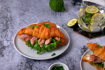 Croissant sandwich with pieces of hot smoked fish catfish clarias on grey table