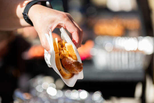 Person serving democracy sausage in white bread with onion on election day at polling station