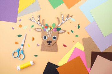 Colorful handmade paper deer head with tools on bright background ideal for toy branding, craft...