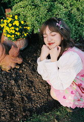 A young girl with a playful expression posing near flowers.