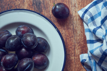 śliwki ,metalowy talerz,stół 