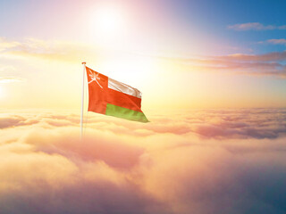 Oman national flag aerial view clouds in beautiful sky. Top view. Drone. Aerial bird's eye fly flag. Aerial top flag view cloudscape. Flag with Sunrise or sunset over clouds.