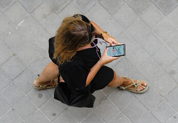 Chica perdida buscando ubicación y localización en app callejero de su móvil con ropa negra y...