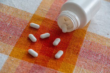 White Oval Pills Scattered From A Spilling Container