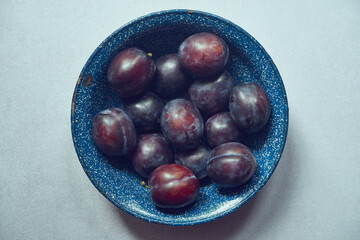 śliwki, metalowa miska ,stół