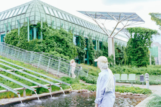 Turkish woman in light hijab and cap looking at eco architecture in Warsaw