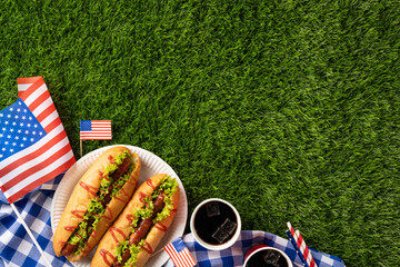 Independence Day picnic setting featuring hot dogs, American flags, and grass backdrop for celebrations