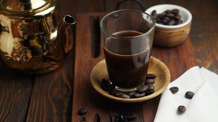 a cup of black coffee with coffee beans on wooden table.